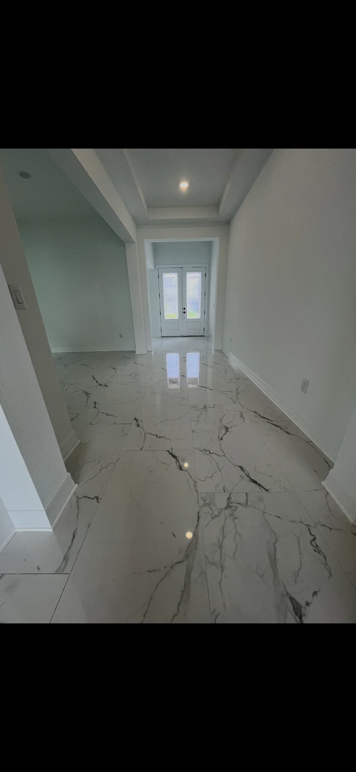 Light gray marble tile flooring with natural veining in modern entryway with white walls