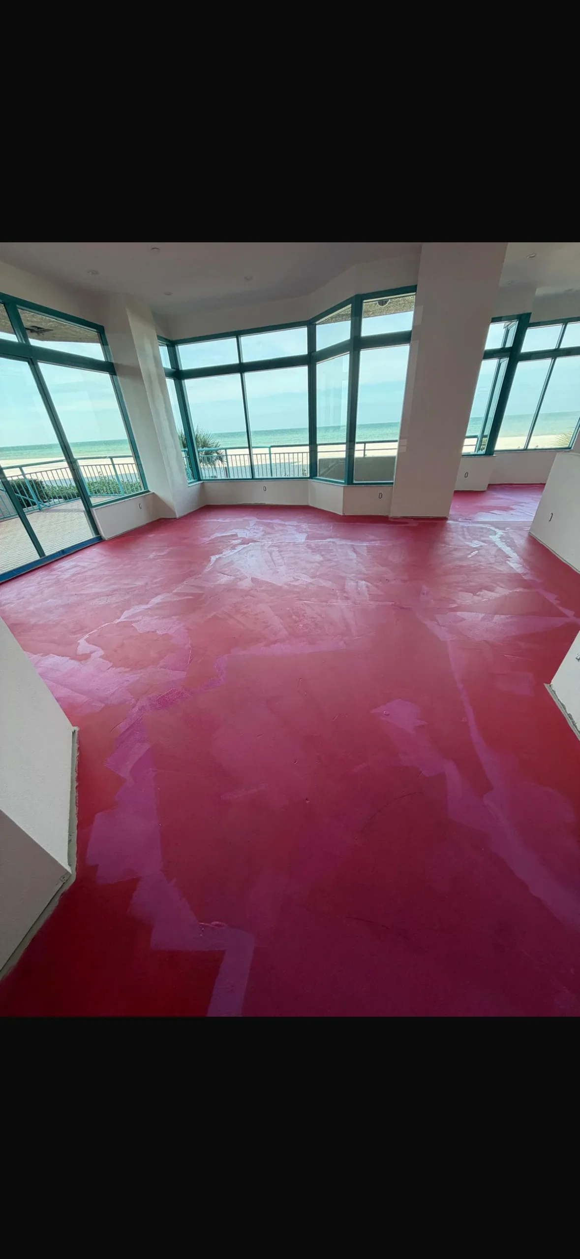 Pink epoxy floor in oceanfront penthouse with floor-to-ceiling windows and ocean view