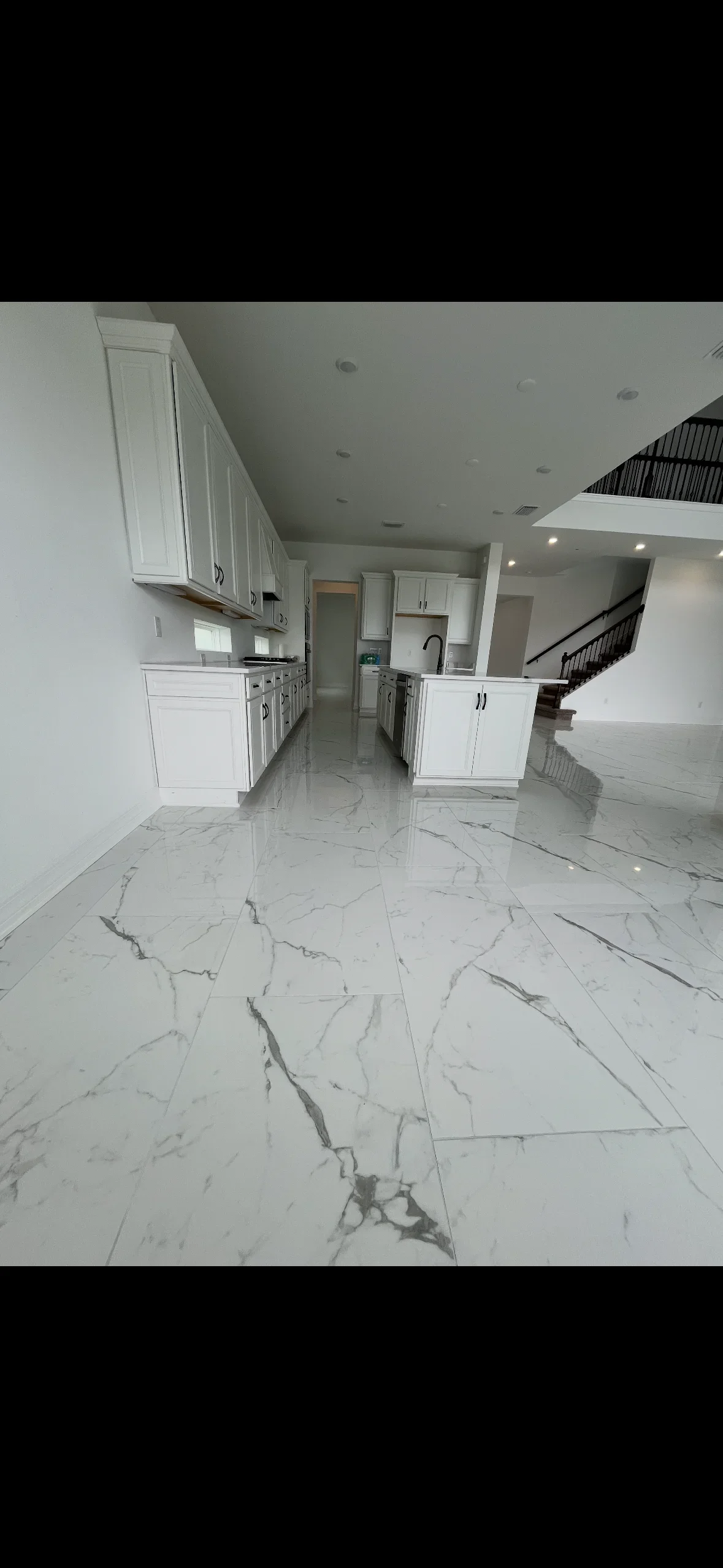 Large-format white marble tile floor with gray veining in modern kitchen with white cabinetry