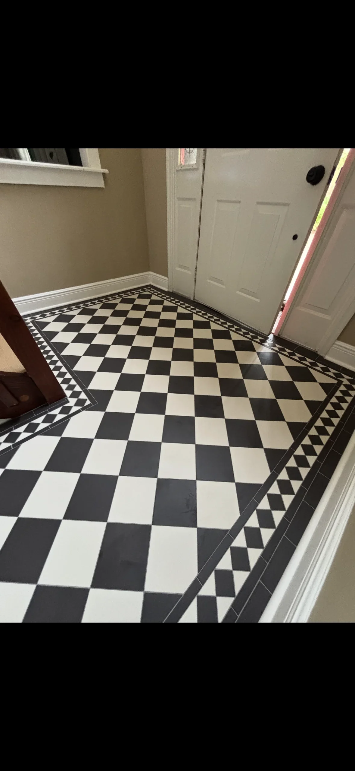 Black and white checkered tile floor with geometric border pattern in entryway