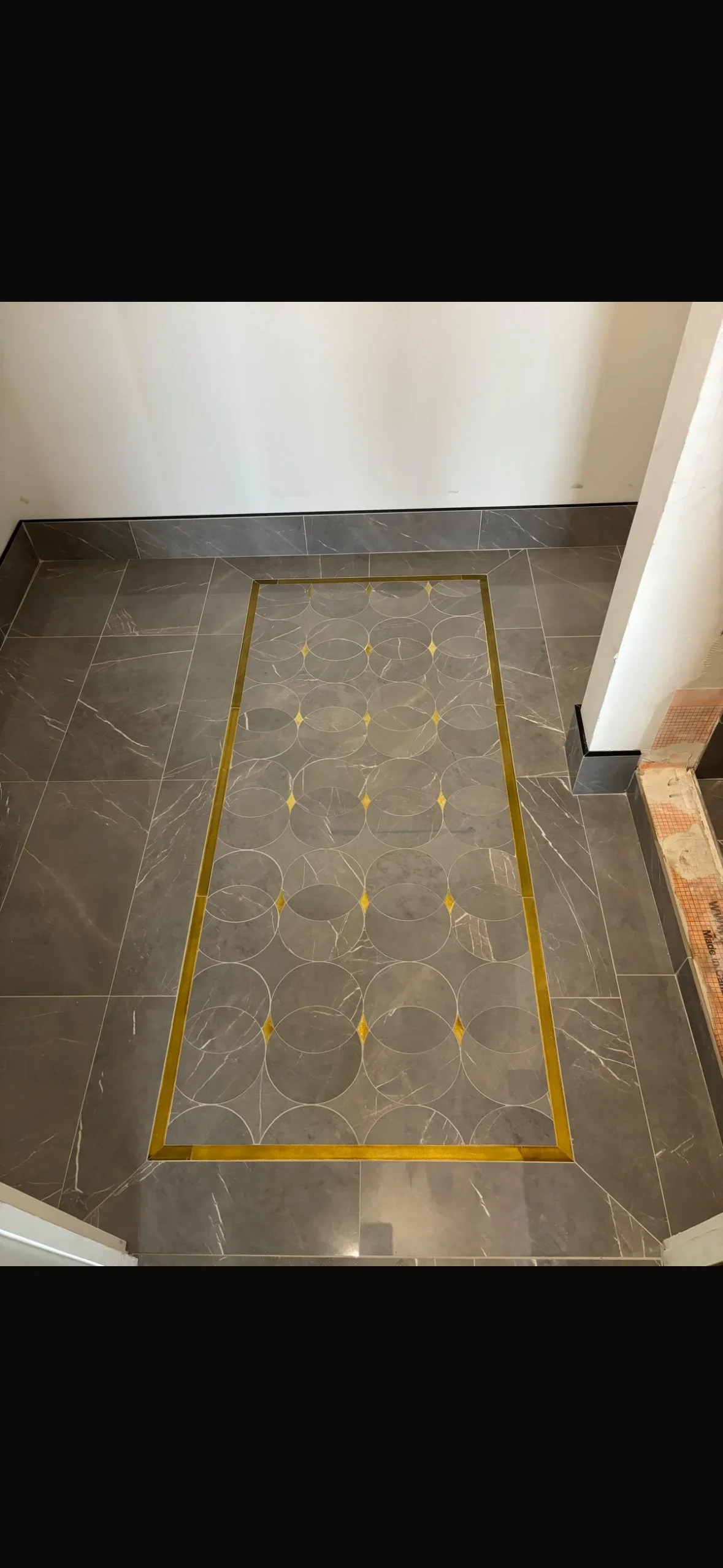 Gray marble tile floor with brass border and circular medallion inlay pattern