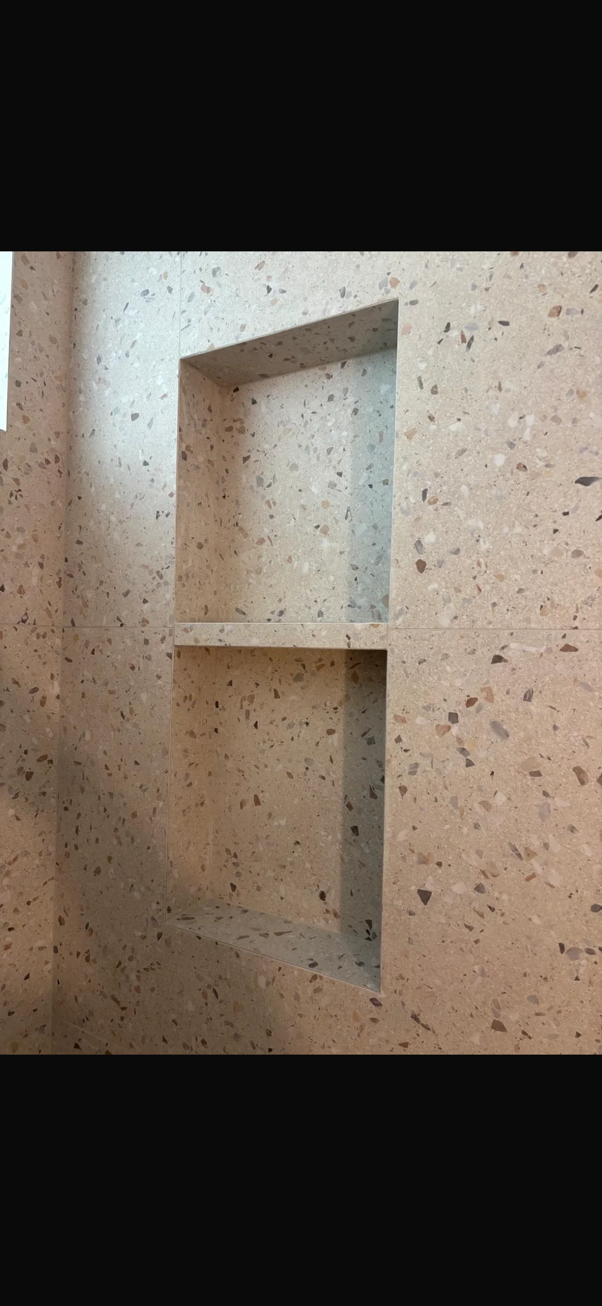 Terrazzo tile niche with speckled aggregate pattern and clean grout lines in wall