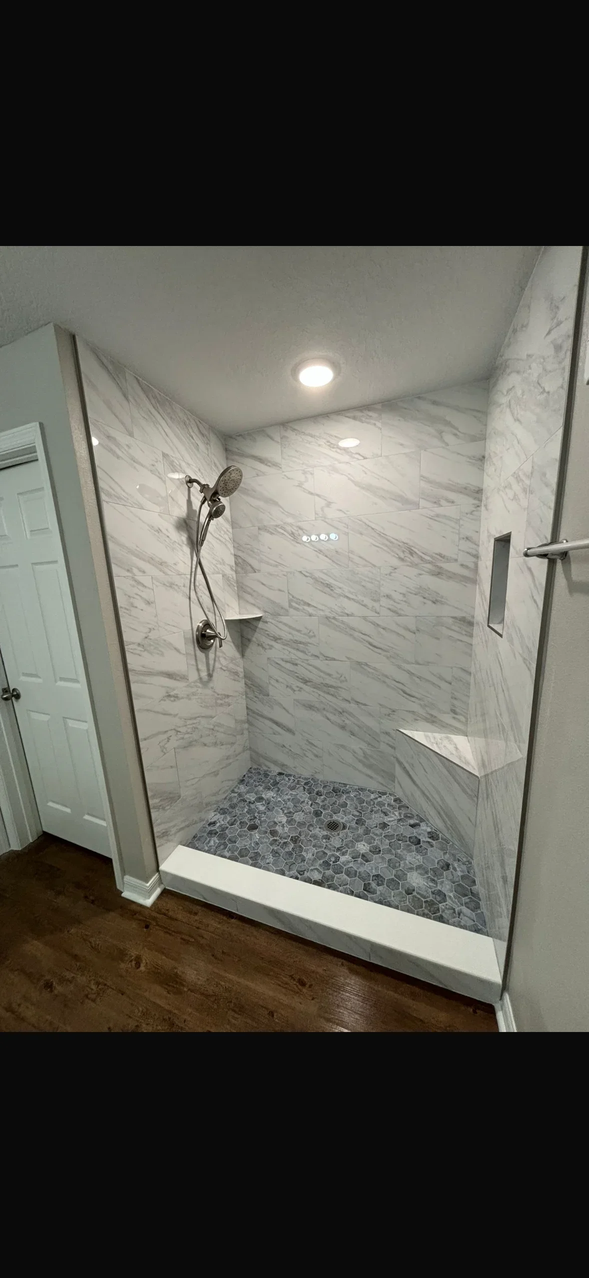 Marble tile shower with hexagonal mosaic floor and dual fixtures