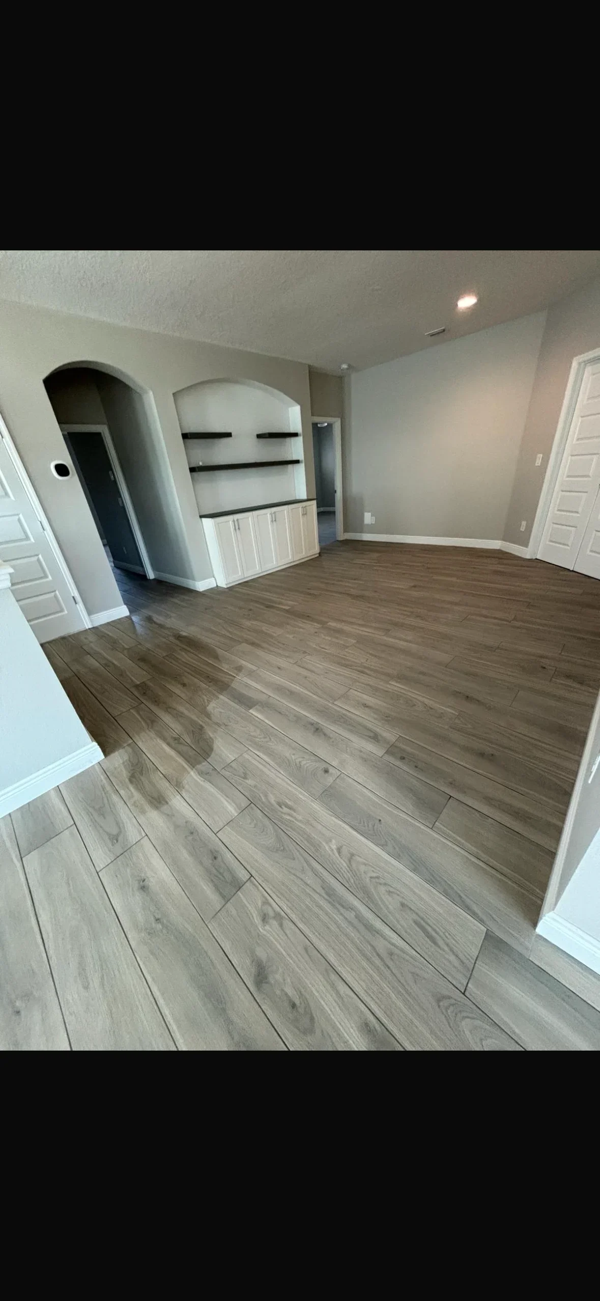 Wood-look plank tile flooring with staggered pattern in residential room with built-in shelving