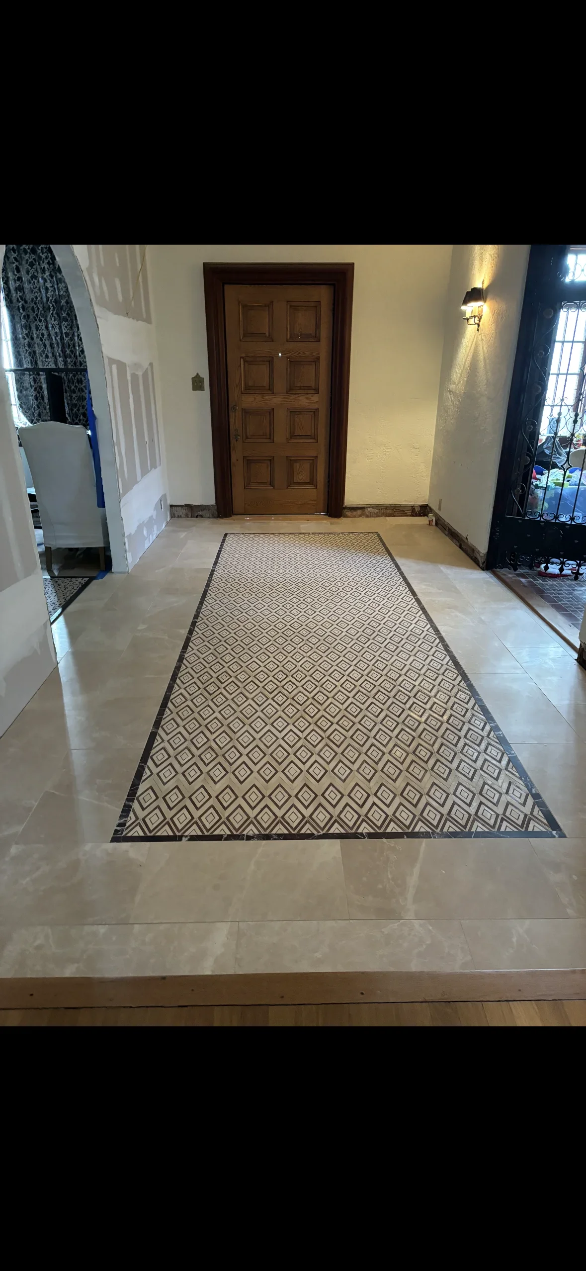 Geometric patterned tile runner with dark border installed in residential entryway over polished concrete