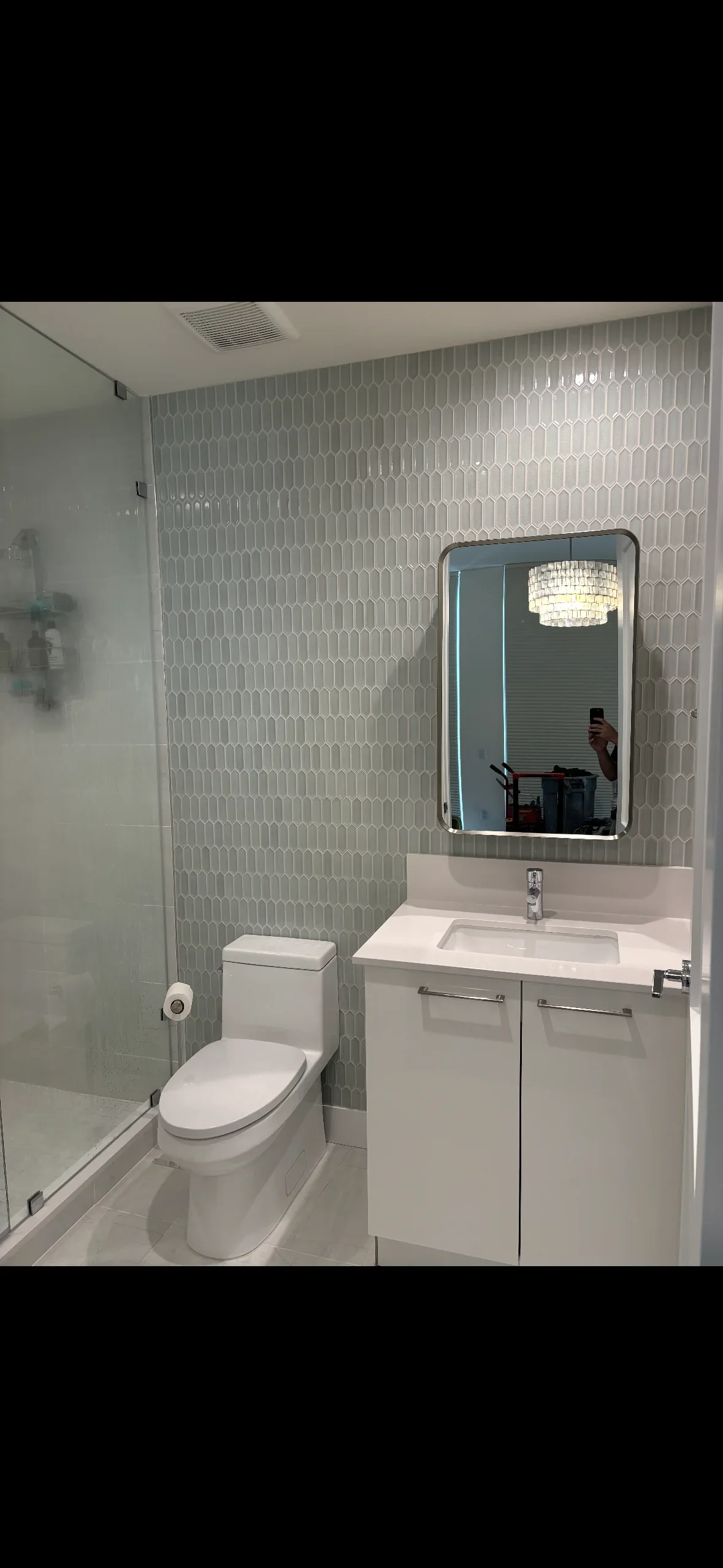 Gray geometric patterned wall tiles in modern bathroom with white vanity and fixtures