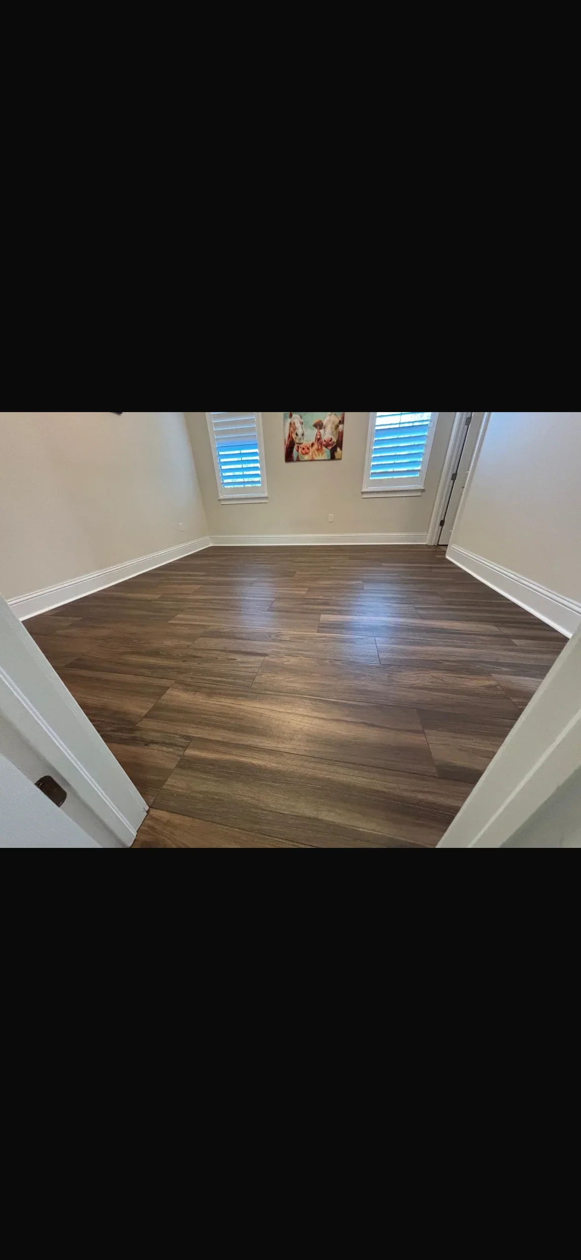 Luxury vinyl plank flooring with wood-tone finish and white baseboards in bedroom