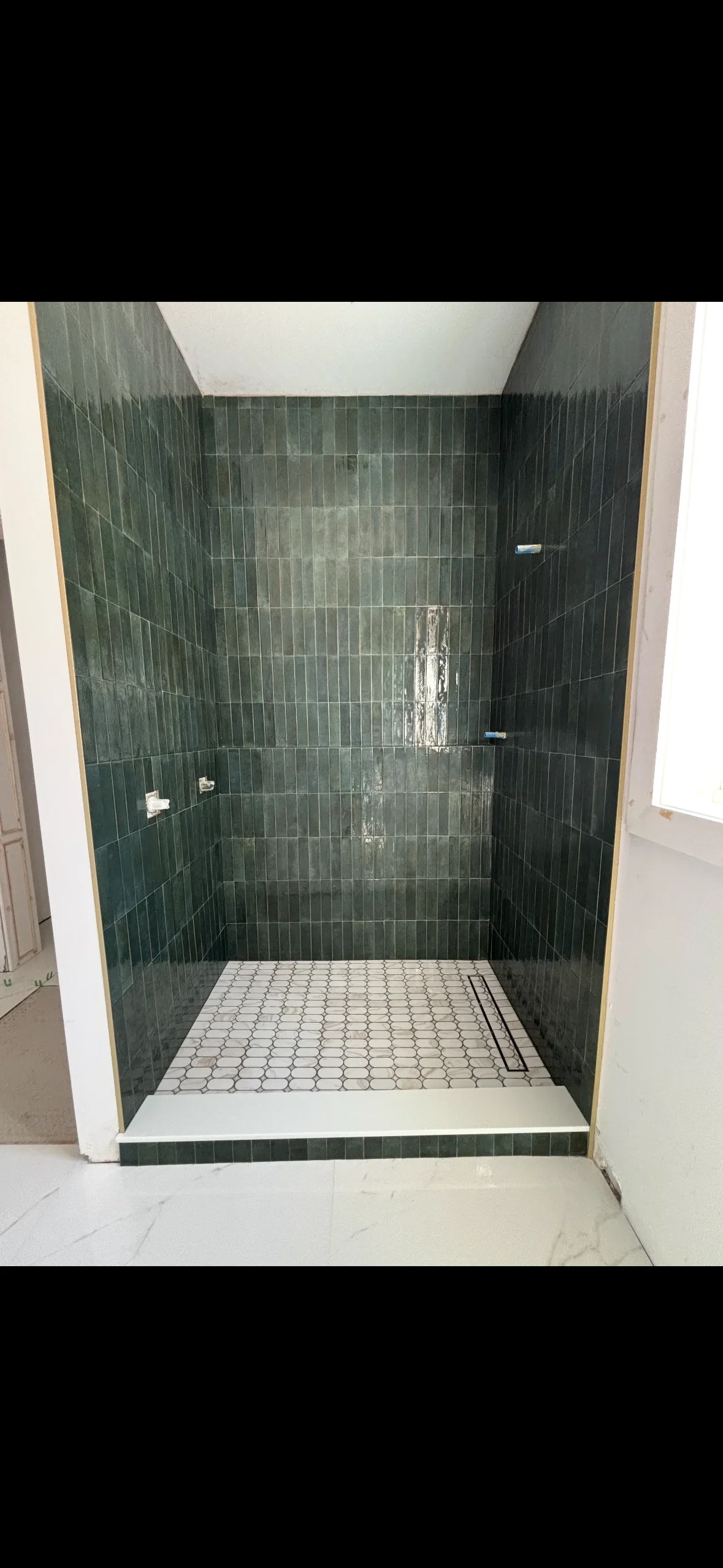 Dark green vertical subway tile shower surround with hexagonal floor tile and chrome fixtures