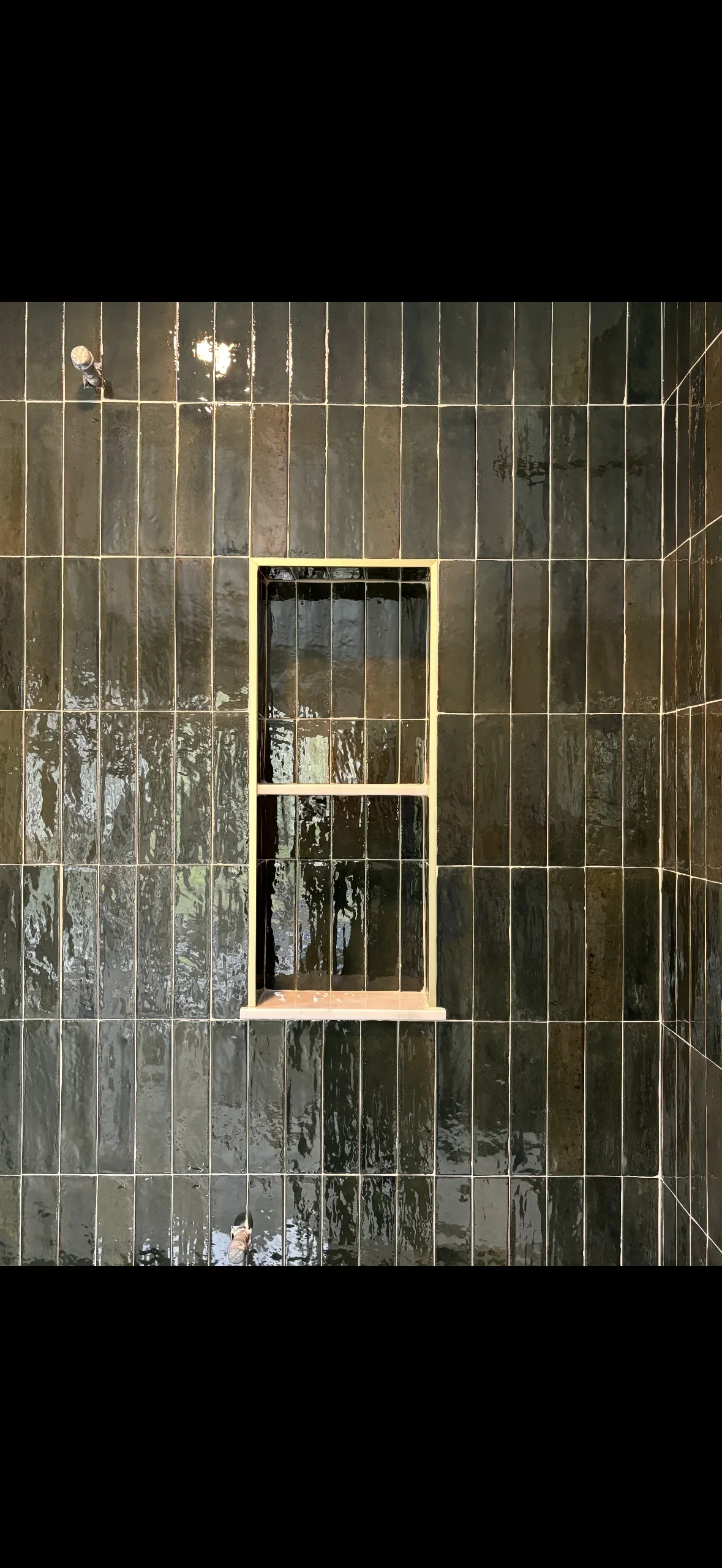 Vertical subway tile wall installation with grout lines and wood-trimmed window opening
