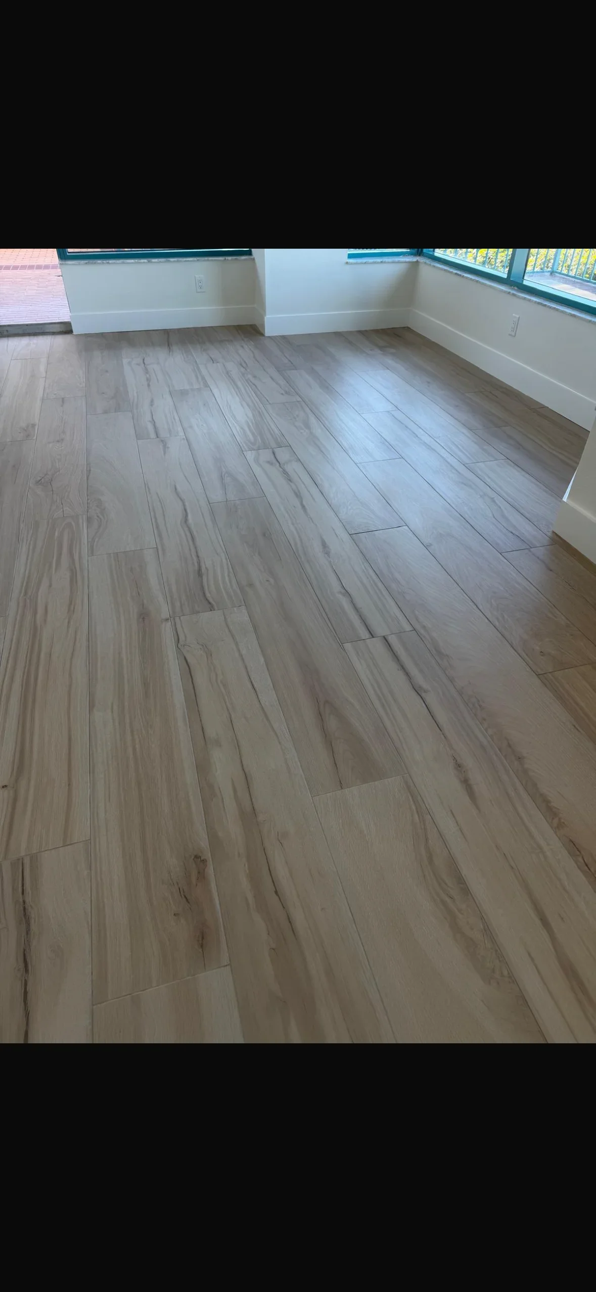 Light gray wood-look porcelain plank tiles installed in staggered pattern with white baseboards