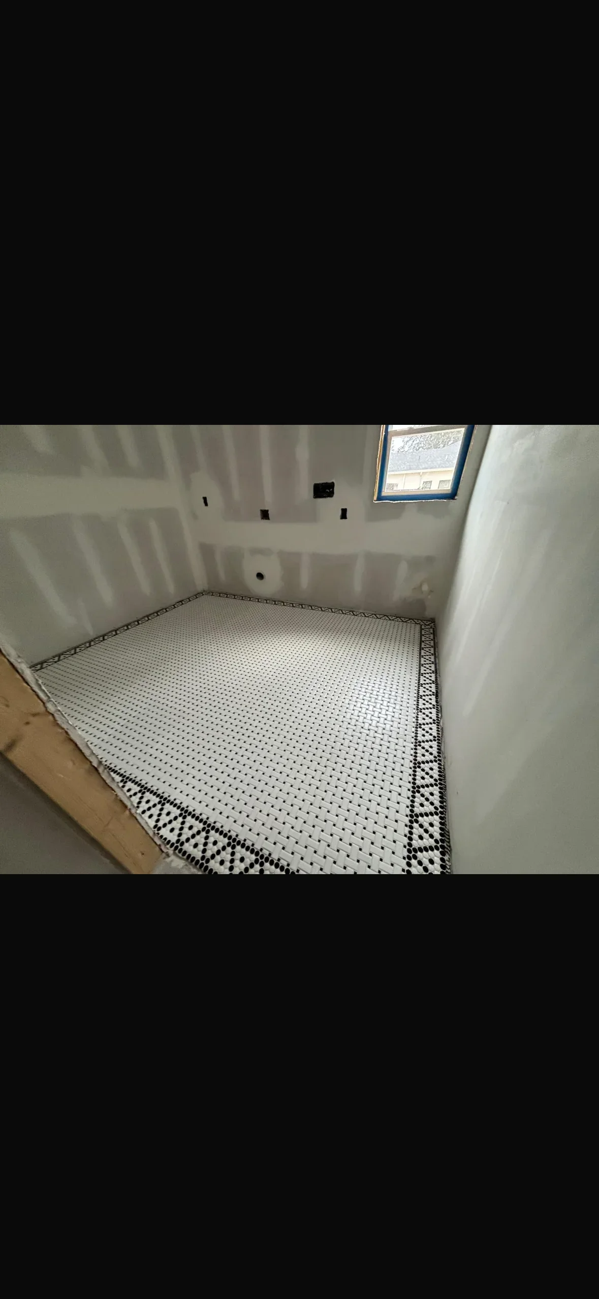 White hexagonal mosaic floor tiles with black grout and decorative border in bathroom