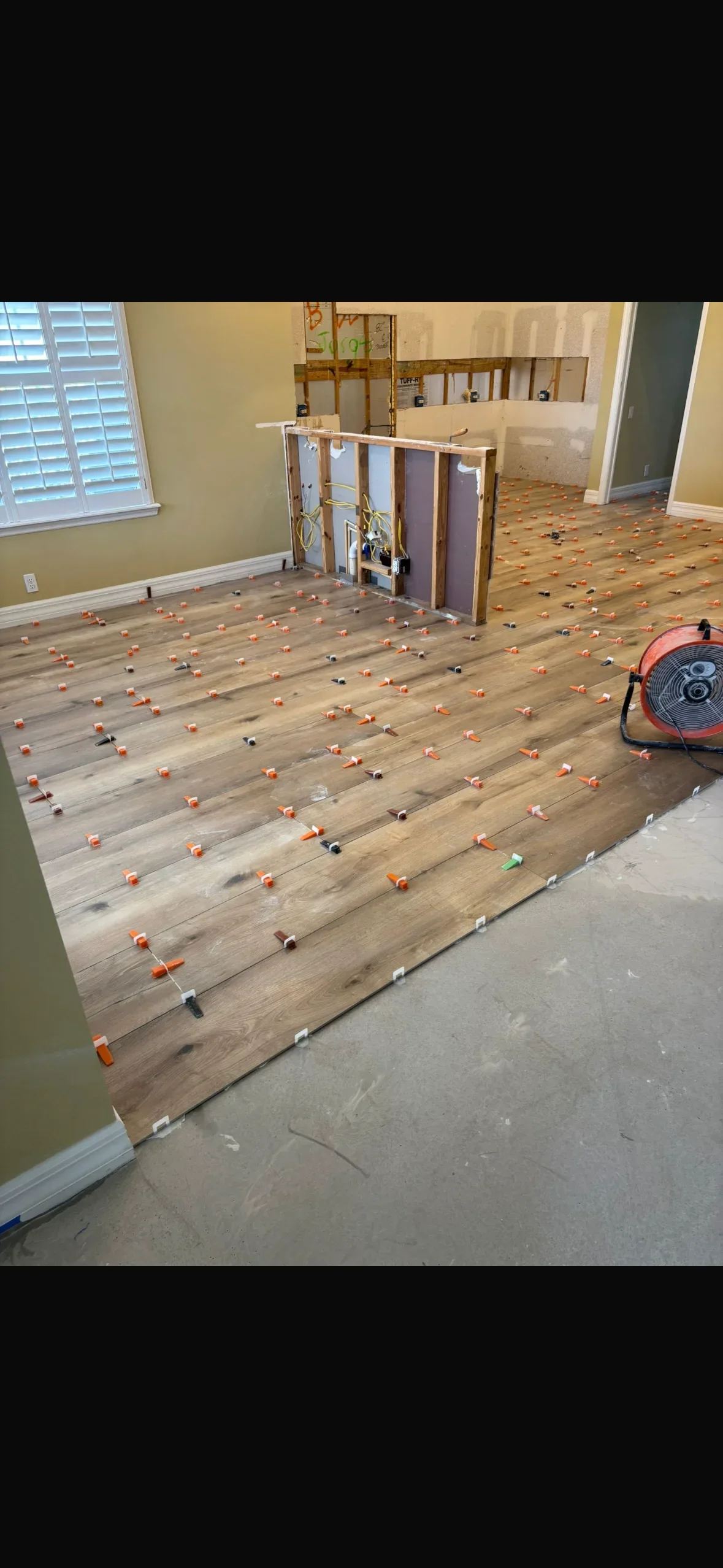 Luxury vinyl plank flooring with orange and black spacers laid out for installation in residential room